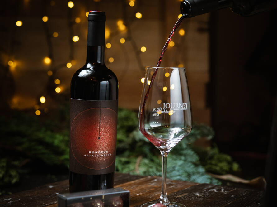 Weinflasche und Glas mit weihnachtlichem Hintergrund und Pralinen